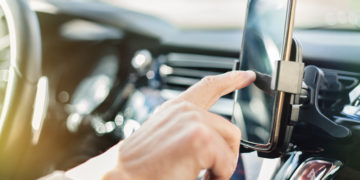 Close up of a man using smart phone while driving