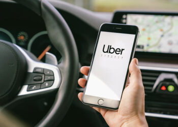 Aachen, Germany September 2019: Uber driver holding his smartphone in car. Uber is an American company offering different online transportation services