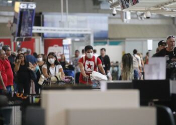 Passageiros e funcionários circulam vestindo máscaras contra o novo coronavírus (Covid-19) no Aeroporto Internacional Tom Jobim- Rio Galeão