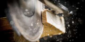 Close-up of carpenter cutting a wooden plank