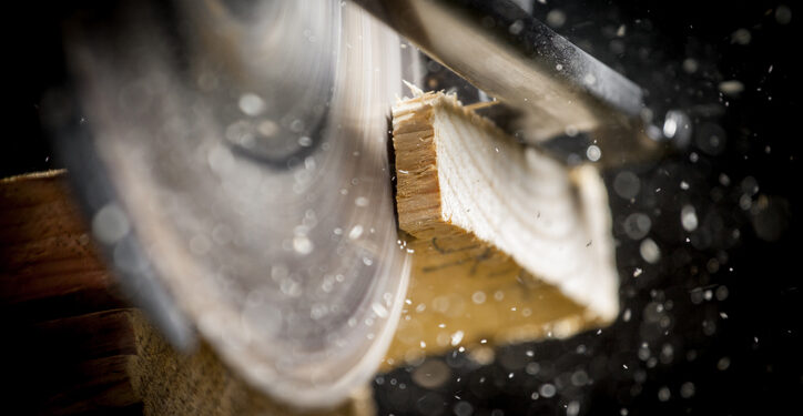 Close-up of carpenter cutting a wooden plank