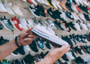 Man holds sports sneakers in his hand in a supermarket